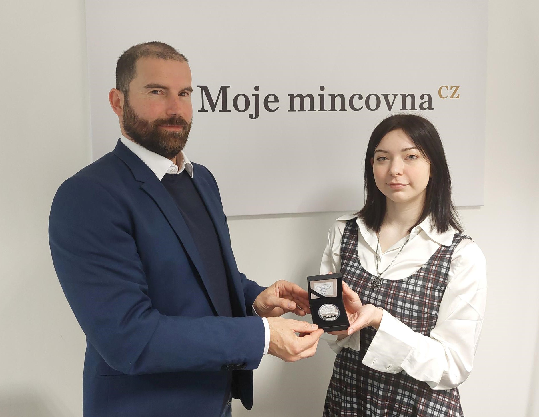 Ředitel Moje mincovna CZ, Libor Veselý, předává první exemplář pamětní ražby autorce vítězného návrhu Michaele Gadziňské.